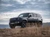 black land rover defender in yellow grass